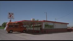 an orange bus is parked in front of a big u's diner on the side of the road