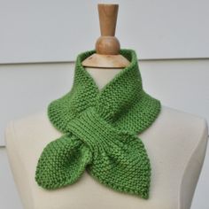 a green knitted scarf sitting on top of a mannequin