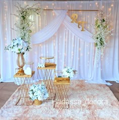 a table topped with vases filled with flowers next to a white wall covered in lights