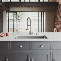 a kitchen with gray cabinets and white counter tops