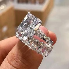 someone is holding an engagement ring that has three princess cut diamonds on it and two baguettes in the middle