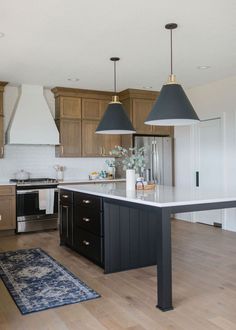 a kitchen with an island and two pendant lights over it's stove top oven