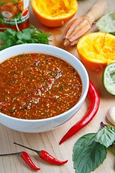 a white bowl filled with chili next to sliced oranges