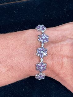 Sterling silver bezel set oval shape  genuine purple amethyst set in a flower pattern with round cubic zirconias set in between each flower and center of each flower.  This bracelet measures 7.5 inches in length with a box and tongue clasp and figure 8 safety. Super whimsical and fun to wear. Nice and smooth edges so it won't catch on anything. Rhodium plated so it will not oxidize.  20.07 grams Elegant Lavender Flower Shaped Jewelry, Flower Shaped Cubic Zirconia Jewelry With Gemstone, Flower Shaped Cubic Zirconia Jewelry With Sparkling Stones, Elegant Flower Shaped Amethyst Jewelry, Fine Jewelry With Purple Sparkling Stones, Purple Flower-shaped Formal Jewelry, Elegant Lavender Flower Jewelry, Purple Flower Shaped Gemstone Jewelry, Flower Shaped Amethyst Jewelry For Anniversary