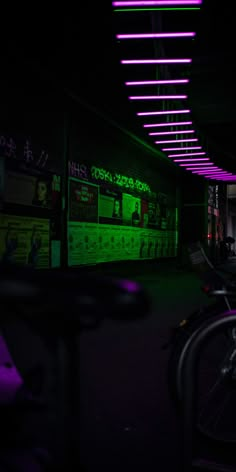 bicycles are parked in the dark with neon lights hanging from it's ceiling above them