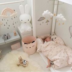 a baby is laying in a crib with stuffed animals on the floor next to it