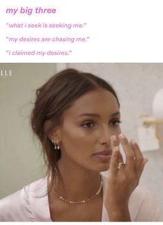 a woman is looking in the mirror while holding her hand up to her face and touching her cheek