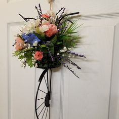 a bouquet of flowers is hanging on the wall next to a white door with a black wheel