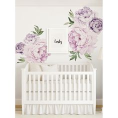 a white crib with purple flowers on the wall