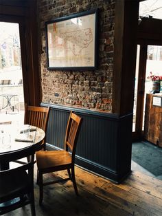 a brick wall in a restaurant with wooden chairs and a map hanging on the wall