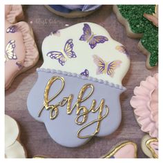 decorated cookies with the word baby in gold letters and butterflies on them, sitting on a table