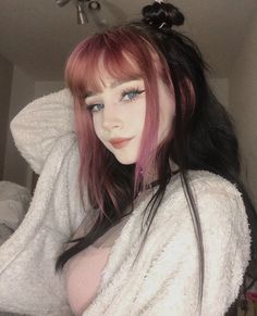 a mannequin with pink hair and blue eyes wearing a white sweater in a room