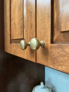 a wooden cabinet with two knobs on the front and one has a teapot in it