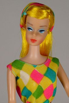 a doll with blonde hair wearing a colorful dress