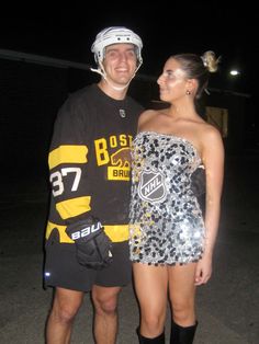 a man and woman standing next to each other in front of a building at night