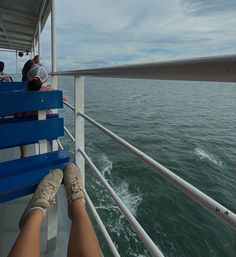 people are sitting on the back of a boat looking out at the water and clouds