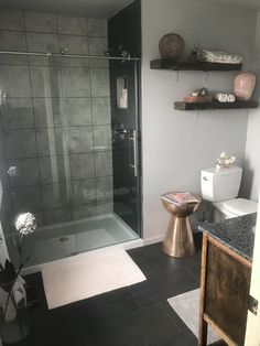 a bathroom with a glass shower door and black tile flooring is shown in this image