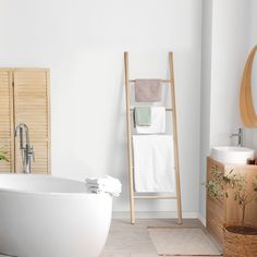 a white bath tub sitting next to a wooden ladder