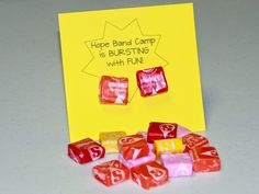 some candy cubes are sitting next to a yellow card with the words hope band camp is busting with fun