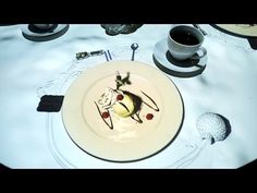 a white plate topped with food on top of a table next to cups and saucers