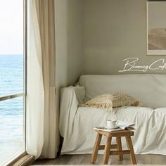 a living room with a couch and coffee table in front of a window overlooking the ocean