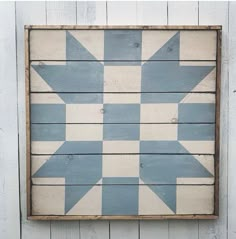 a blue and white wooden wall hanging on the side of a building with an arrow painted on it