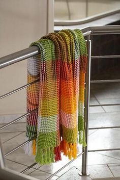 multicolored towels are hanging on a metal railing