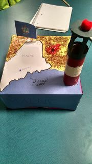 a small box with a map on it sitting on a table next to a vase