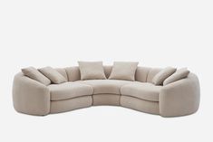 the curved sofa has four pillows on it and is in front of a white background