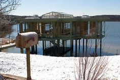 a house built into the side of a lake with snow on the ground and trees around it