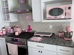 a pink stove top oven sitting inside of a kitchen next to a microwave and toaster oven