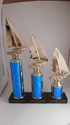 three blue and gold sailboats on black bases