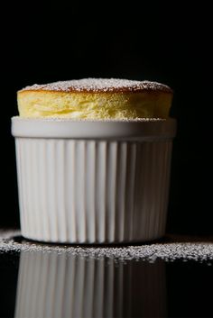 a close up of a pastry in a white dish on a black surface with snow flakes