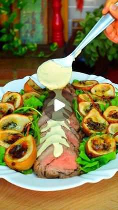 a plate with meat and vegetables on it being drizzled with mayonnaise