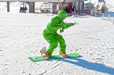 a man dressed in green riding a snowboard