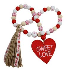 a red and white beaded necklace with a heart shaped charm hanging from it's side