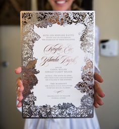 a person holding up a wedding card in their hand, with the text on it