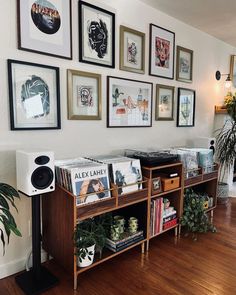 there are many framed pictures on the wall above this record player's console table