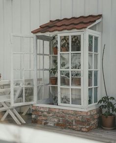 a small white house sitting on the side of a building next to a table and chairs