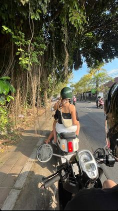 a man riding on the back of a motorcycle down a street next to a parked car