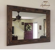 a mirror hanging on the wall with a wreath in front of it and a ceiling fan