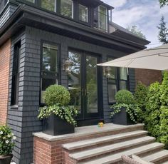 a house that has some plants in front of it and an umbrella on the steps