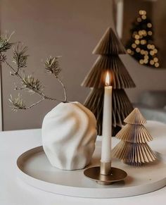 a white candle sitting on top of a plate next to a christmas tree and other decorations