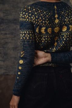 a woman with her back to the camera, wearing a black and gold top that has flowers on it