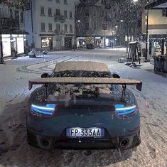 a car parked in the middle of a snowy street with its hood up and lights on