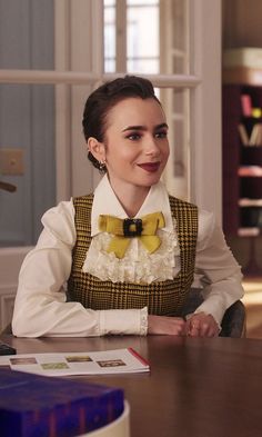 a woman sitting at a table wearing a bow tie