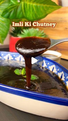 a spoon is pouring chocolate into a bowl with leaves on the table next to it