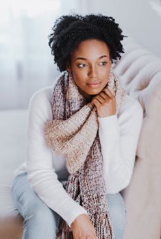 a woman sitting on top of a couch wearing a scarf