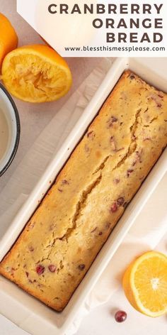 a loaf of cranberry orange bread on a plate next to sliced oranges