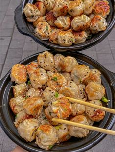 two black plates filled with dumplings and chopsticks on top of each other